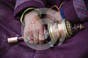 Old hands of a Tibetan woman holding prayer buddhist wheel at a Hemis monastery, Leh district, Ladakh, Jammu and Kashmir, north In