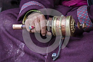 Old hands of a Tibetan woman holding prayer buddhist wheel at a Hemis monastery, Leh district, Ladakh, Jammu and Kashmir, north In
