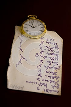 Old handwritten sheet and a pocket clock