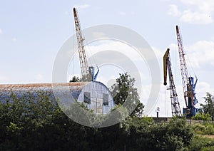 Old hangar and cranes against the blue sky