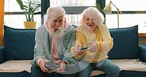 old happy granndmother is winning grandfather while playinbg computer game