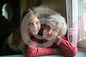 An old happy lady posing for a portrait with little girl great-granddaughter