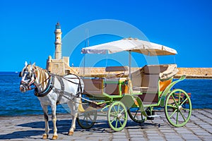 The old harbor of Chania with horse carriages, mosque and lighthouse.