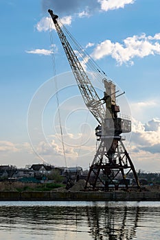 An old harbor crane is waiting for the ship