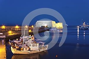 Old harbour of Heraklion with Venetian Koules Fortress, boats and marina at night, Crete.