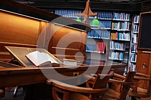 old hard cover book sitting at an old traditional timber reading desk under a glass lamp in an old state library in Melbourne,