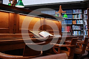 old hard cover book sitting at an old traditional timber reading desk under a glass lamp in an old state library in Melbourne,