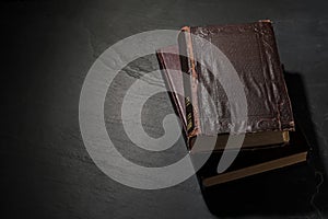 Old hardcover books on black textured table, space for text