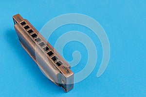 Old harmonica on a blue background.