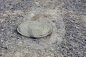 Old hatch cover on the gray road