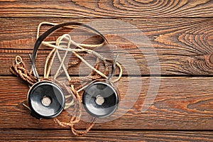 Old headphones. Top view of vintage radio headphones with fabric wire on wooden background. Ancient radio engineering concept with