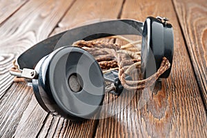 Old headphones. Vintage headphones with a cloth wire on a wooden background. The concept of ancient radio engineering