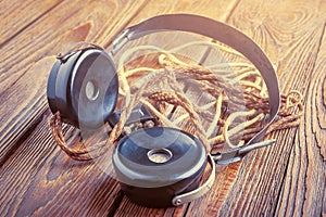 Old headphones. Vintage headphones with a long cloth wire on a wooden background. The concept of ancient radio engineering