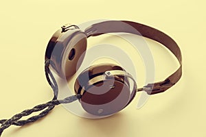 Old headphones. Yellow toning vintage headphones on a light background. The concept of ancient radio engineering