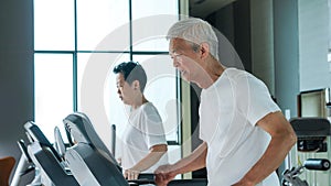 Healthy Asian senior couple exercise together in gym running treadmill