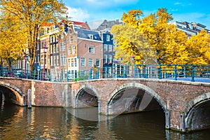 Old heart of Amsterdam. Beautiful autumn, golden falling leaves, old sloping houses, bridges and canals. Autumn day in Amsterdam.