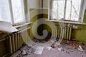 Old heating radiators under the windows of an abandoned kindergarten in a village in the Chernobyl exclusion zone