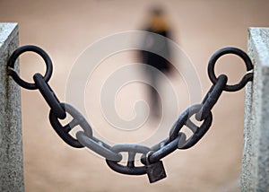 An old heavy iron chain hung between two granite slabs and a lock, a symbol of love, hung on it with a blurred background of a