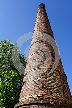 An old high factory chimney against a blue sky