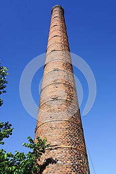 An old high factory chimney against a blue sky