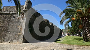 Old high fortifying wall in city with sidewalk along it, panorama and sequence