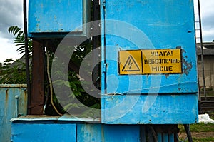 Old high voltage transformer sign on blue metal board