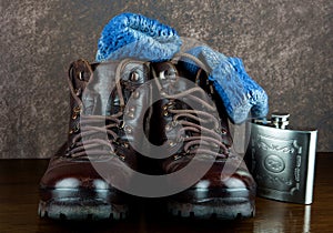 Old Hiking Boots with Boot Socks and Hip Flask on a Wooden Shelf