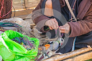 Old hill tribe woman make a handicraft bracelet