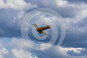 Old historic biplane fly on cloudy sky from side