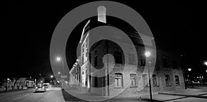 An old, historic brewery at night, illuminated by street lamps and spotlights .