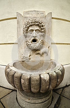Old historic fountain on the facade of a house in the shape of a face with open mouth, Bratislava