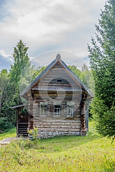 Old historic log house in rural Russia, Siberia surrounded by summer forest.