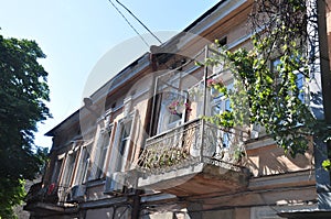 Old historic stone house on the yard with trees around. Old city buildings before and after restavration. Ancient windows, roofs, photo