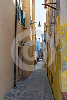 Old, historic, very narrow street with colorful old houses and cobblestone pavement. Venice, Italy