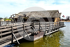 Old, historic wooden floating boat mill on green river water.