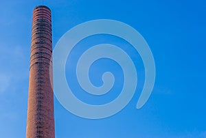 Old historical stone chimney burner, old factory architecture, blue sky in the background