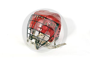 An old hockey helmet of red color with a protective iron mask on a white background