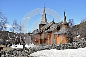 Old Hol Gamle Kyrkje church building stands in the countryside, near a winding road