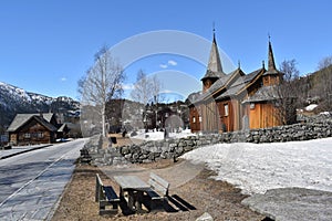 Old Hol Gamle Kyrkje church building stands in the countryside, near a winding road