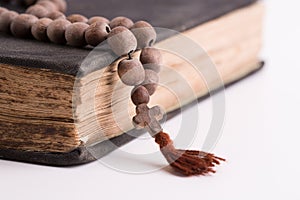 Old holy book and rosary of a priest on a light background