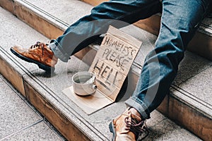 Old homeless person sleeping on stairs with cardboard with dollar in can