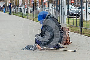 Old homeless woman is sitting on street and begging money