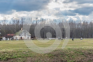 Old horse farm with rural houses and horses grazing in the field