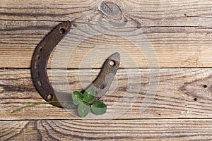 Old horseshoe and four leaf clover on old wooden boards. St. Patricks day, lucky charms