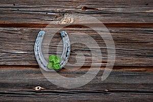 Old horseshoe and four leaf clover on a vintage wooden board. The concept of luck, luck, luck. St. Patricks Day card