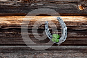 Old horseshoe and four leaf clover on a vintage wooden board. The concept of luck, luck, luck. St. Patricks Day card