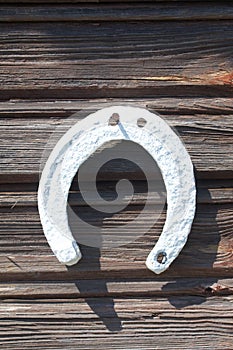 An old horseshoe hangs on a log wall. Painted white. Close-up