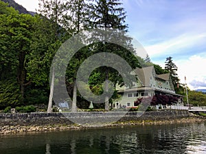 An old hotel beside the ocean surrounded by tall evergreen trees in British Columbia, Canada