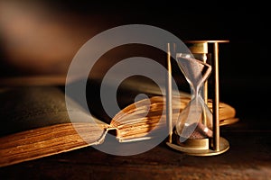 Old hourglass and ancient book with open pages