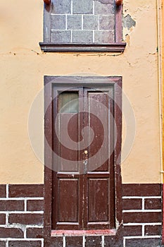 Old house or church with peeling paint on wall or window and wooden shutter door. Vintage and aged residential building